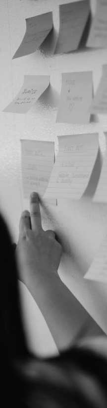 Persona señalando con la mano notas adhesivas pegadas en una pared durante una sesión de trabajo